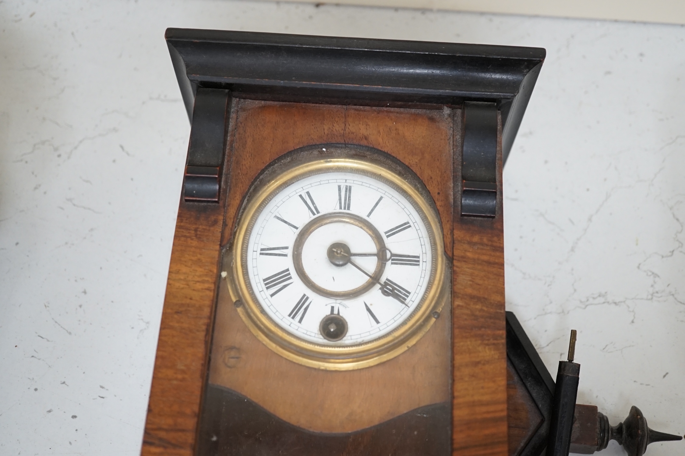 A small walnut cased wall clock with enamel dial with pendulum and key. Condition - poor